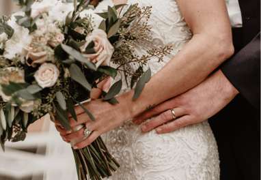 a bride and groom holding a bouquet of flowers