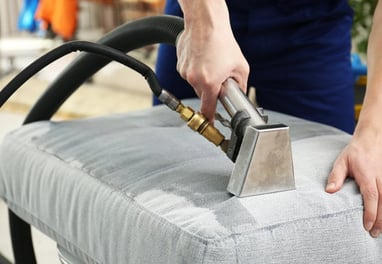 a person cleaning a couch with a vacuum