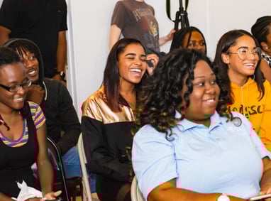 a group of people sitting in chairs in a room, smiling and enjoying a creative Christian event