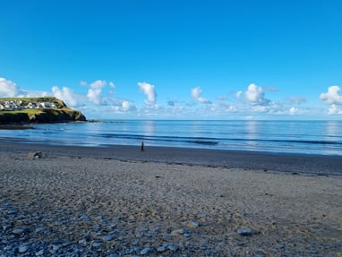 Borth beach with smooth glassy sea blue sky and fluffy clouds
