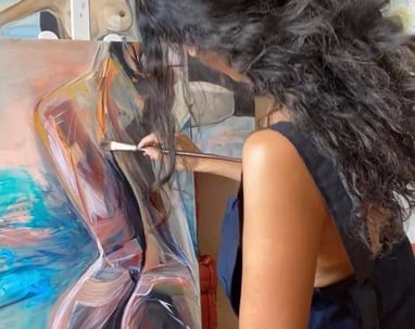 Sherezade Morales painting a captivating woman's silhouette on canvas.