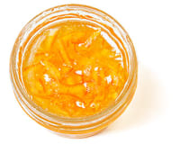 Top down view of a little, clear, open container of orange marmalade with peel slices
