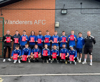 Team photo where the players are holding up anti-racism cards reading "show racism the red card"