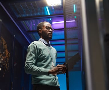 a man in a server room with a laptop