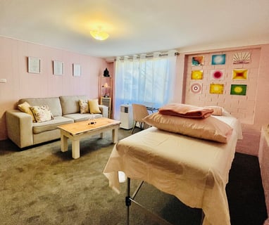 healing room with table, couch and massage table in pink