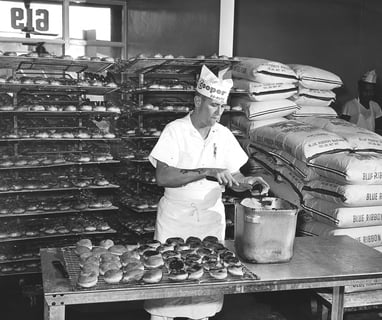 Cooper Donuts - Mr. Richard Evans glazing chocolate donuts.
