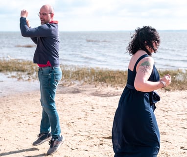 Couple sautant et riant lors d'une séance photo au bassin d'arcachon