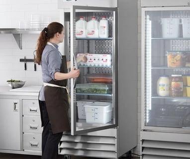 a woman in a apron and aprons is standing in front of a refrigerator