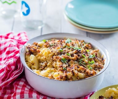 Mac and Cheese in a tin bowl with a crunchy topping and a checked napkin to the side