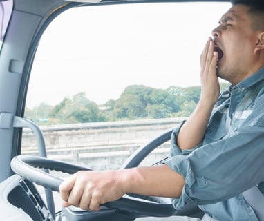 a man in a blue shirt is sitting in a truck yawning