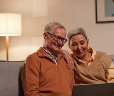 an older man and woman sitting on a couch