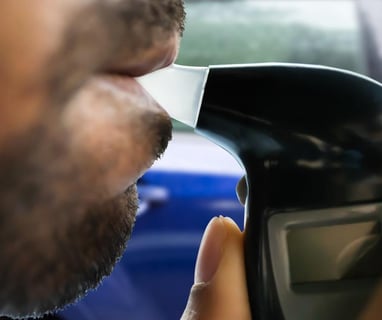 a man with a beard blowing into a breathalyzer