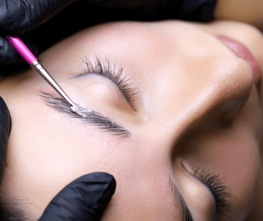 a woman getting her eyebrows laminated by a professional brow artist