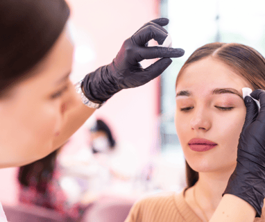 a woman getting her eyebrows done by a professional brow artist