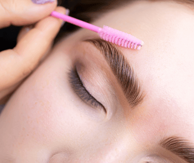 a woman brushing her brows after eyebrow lamination