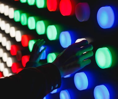 a person holding a remote control device in front of a wall of colored lights