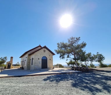 a small Orthodox church in Cyprus with a large tree in the background