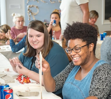 Individuals at a private party laughing as they begin their clay project.