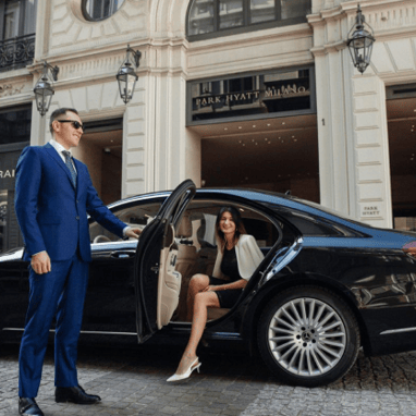 a man and woman in suits and ties standing in front of a car