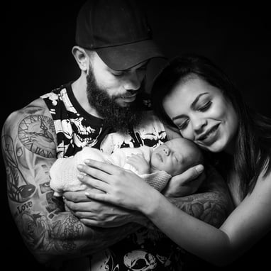Um casal segundo seu bebê recem nascido em uma foto emocional em preto e branco