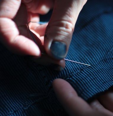artist sewing her own textiles dyed in her indigo vat
