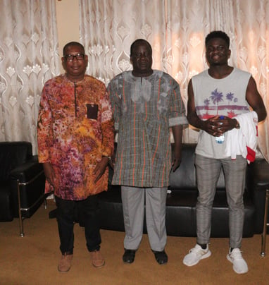 three men standing in front of a couch