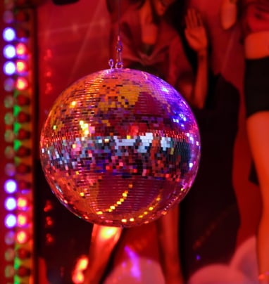 a photograph of a disco ball in front of an image of people dancing.