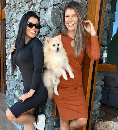 two women standing next to each other in front of a stone wall