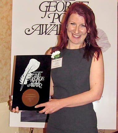 A woman in a gray dress holding a plaque
