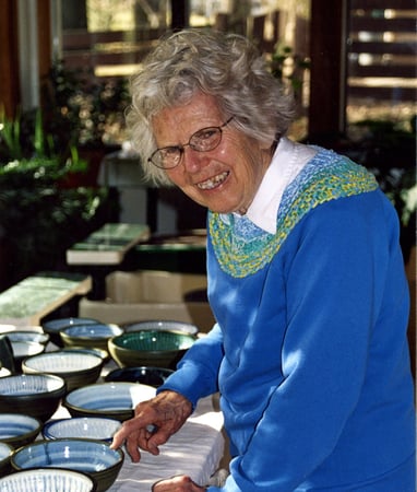 One of our founders, Naoma Powell, pictured with a table full of bowls she made.