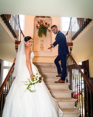 a bride and groom walking down the stairs of a staircase