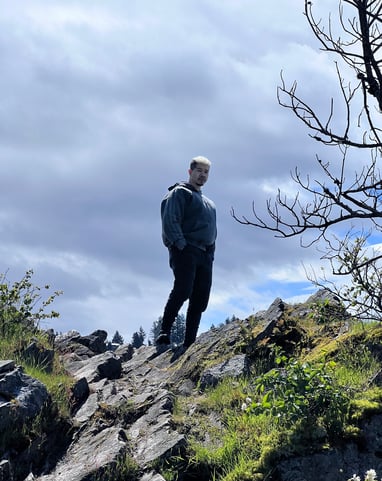 a man standing on a rocky cliff with a tree in the background