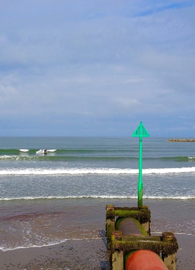Clean waves in Borth with a longboarder riding one with blue skies