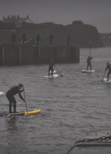 A paddle board race in Aberystwyth harbour on a grey December day