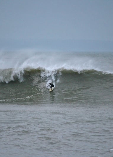 A surfer rides a big wave during winter