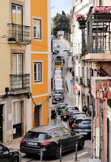 Yellow tram 28 follows very scenic route on a very steep curved street of Lisbon