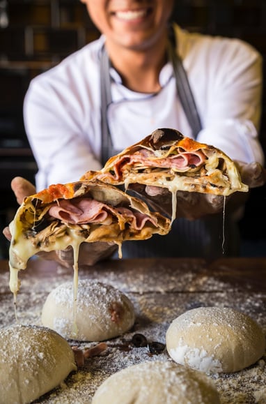 person making and baking fresh pizza