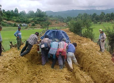 A team pushing a vehicle along a muddy track