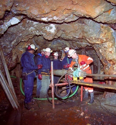 A group of people in a cave like area with old mining machinery