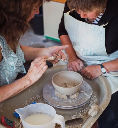 Two people around a potters wheel making a bowl