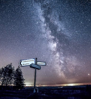 a street sign with a milky way like sky in the background