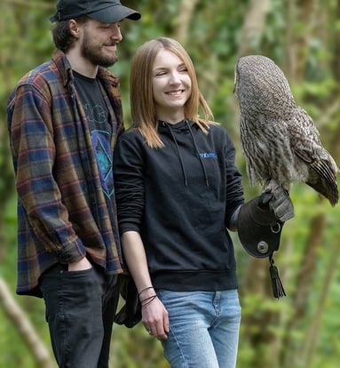 a man and woman standing next to each other with a bird of prey