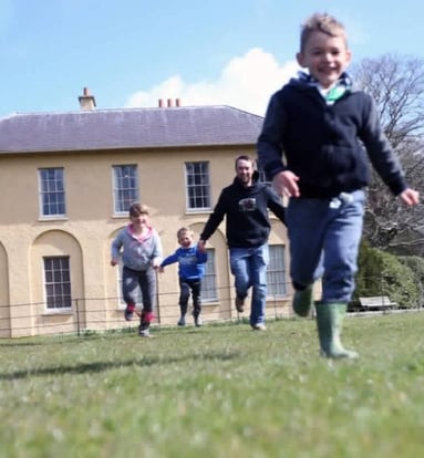 A family running in front of an historic house