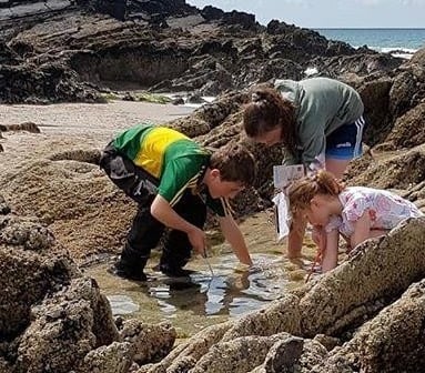 a woman and two children playing in the water