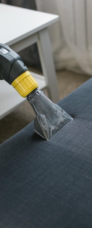 a person using a vacuum cleaner to clean a couch