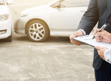 Perito automotriz inspeccionando detenidamente un siniestro de coches, tomando notas