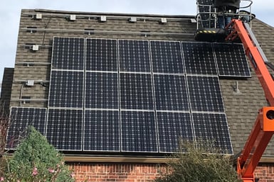 a man on a lift platform working on a solar paneled roof