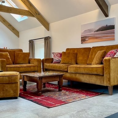 A room with ochre coloured soft seating and a colourful rug