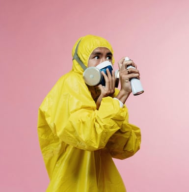 Man looking afraid in full ppe with a spray bottle