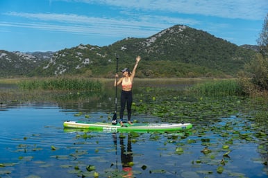 a woman standing on a paddle board on lake